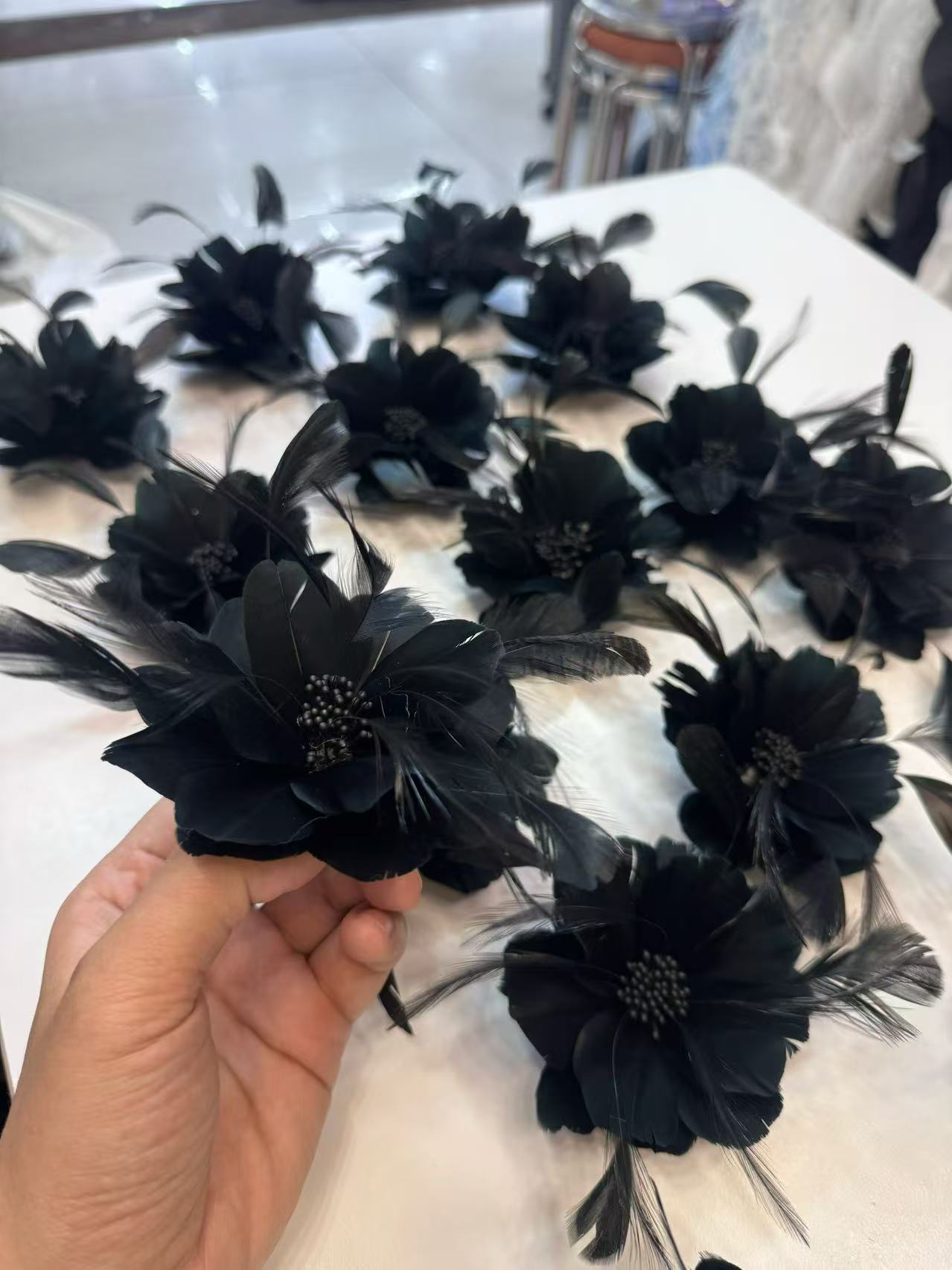 Black dimensional flower appliques with feather details arranged on a worktable